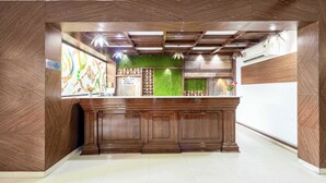 A reception area with a wooden counter, green artificial grass wall, and a 'No Check-in Without Proof' sign. - Treebo Maurice (Baddi)
