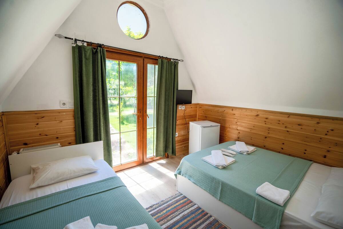 A room with two beds, a small TV, and a window with curtains.