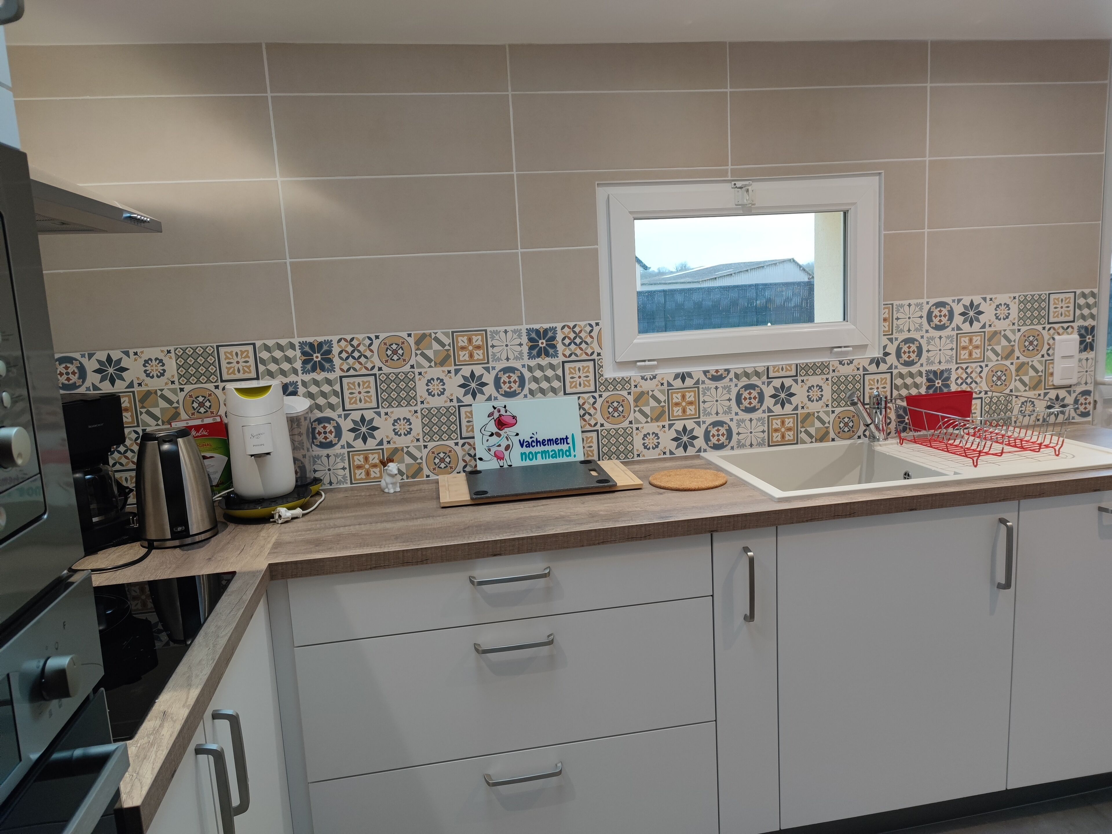Una cocina con salpicadero de azulejos, una ventana y un lavamanos.