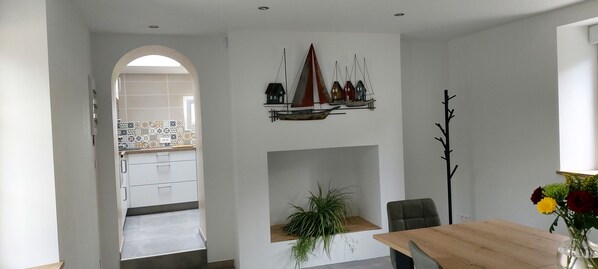 Una cocina moderna con armarios blancos, un salpicadero de azulejos y una mesa de comedor de madera con sillas.