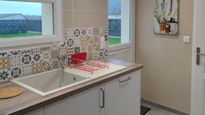 Una cocina moderna con un ventanal grande, un salpicadero de azulejos y un escurreplatos.