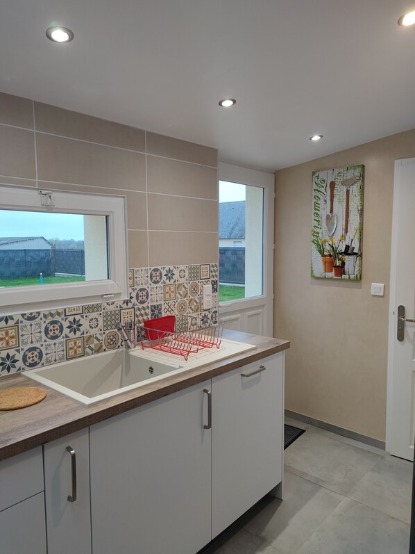 Una cocina moderna con un ventanal grande, un salpicadero de azulejos y un escurreplatos.