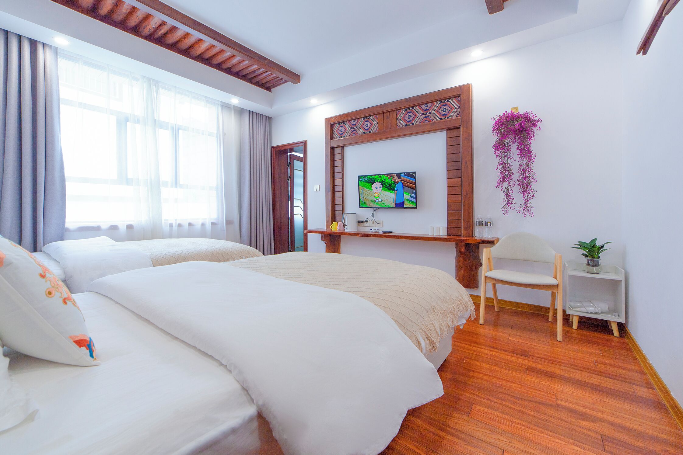 A hotel room with a large bed, a TV mounted on the wall, and a wooden floor.
