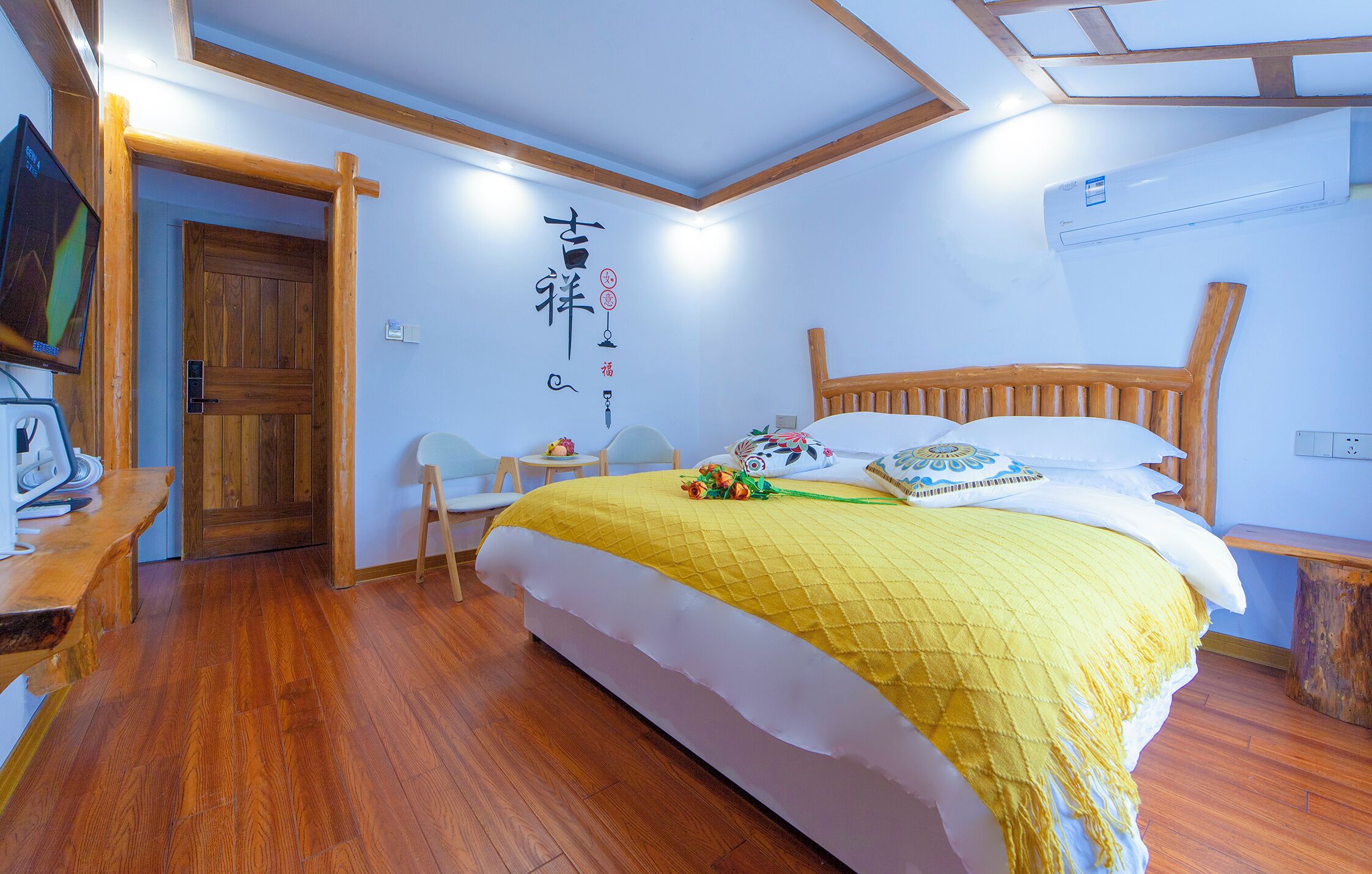 A bedroom with a wooden bed, a desk with a computer, a chair, and a wooden door.