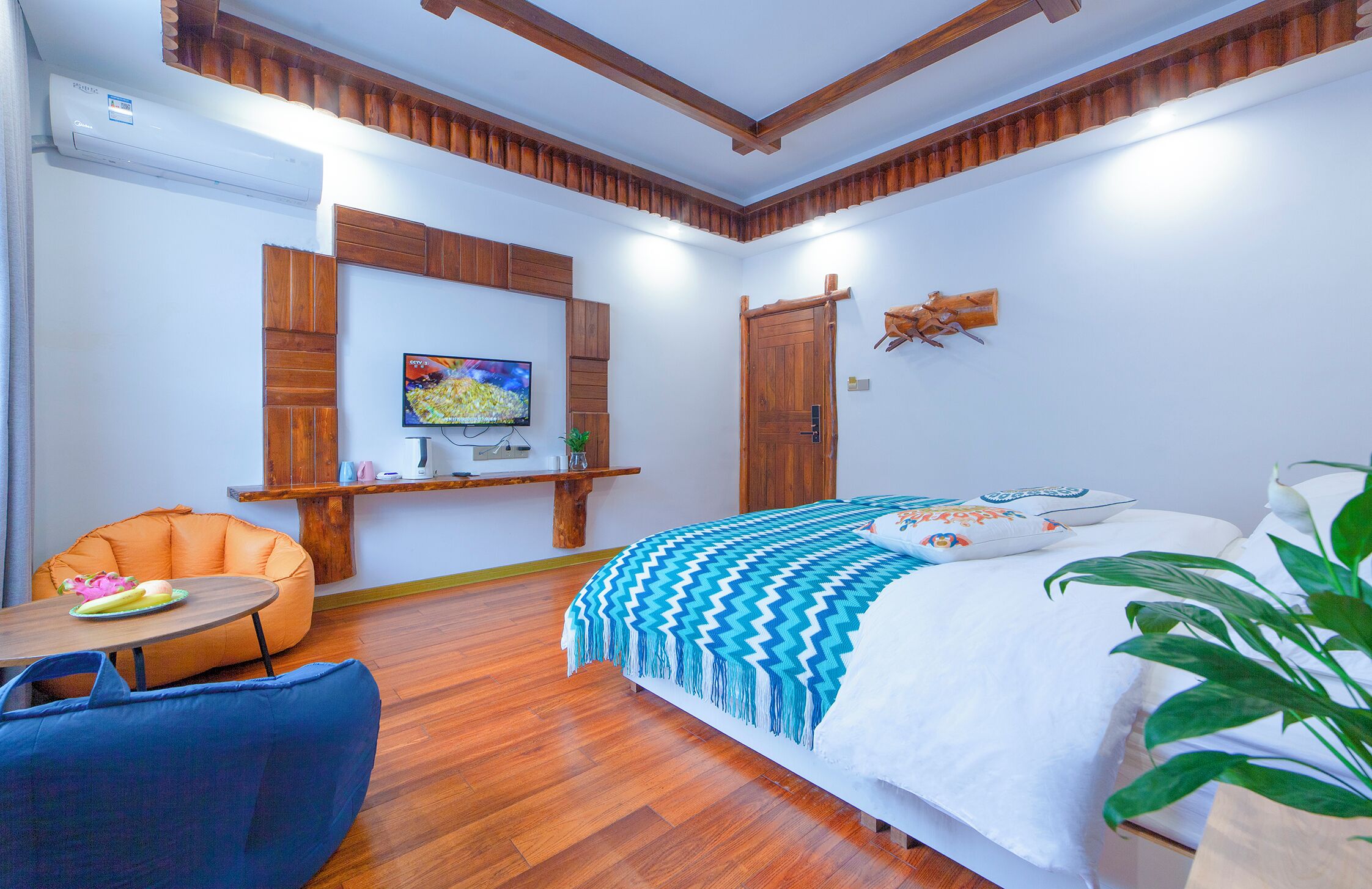 A bedroom with a bed, a wooden ceiling, a TV on a shelf, a chair, and a plant.