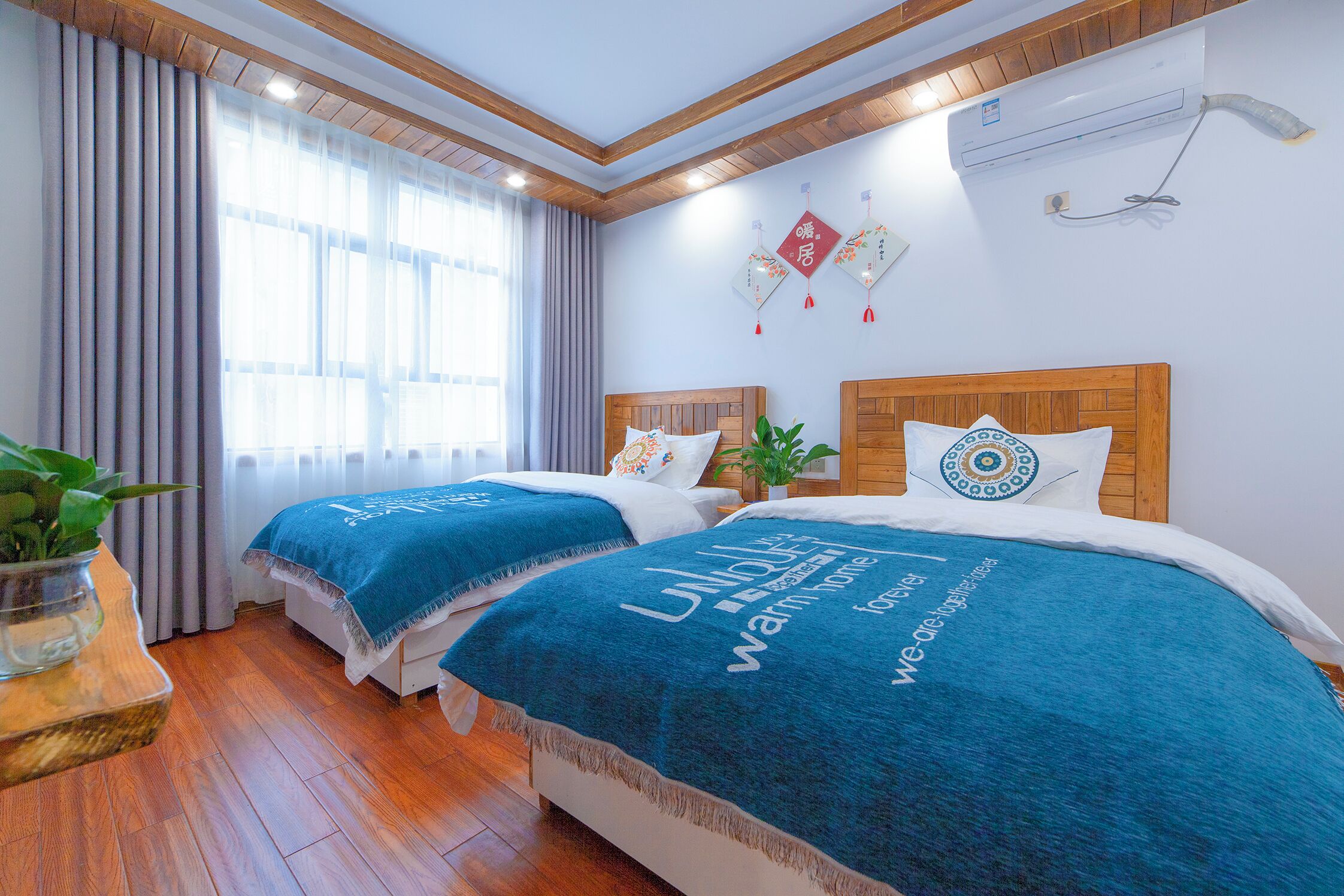 A hotel room with two beds, wooden headboards, and a large window with curtains.