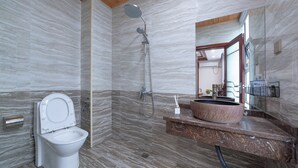 Ein modernes Badezimmer mit Marmorboden, Toilette, Dusche mit Handbrause und großem Waschbecken mit Marmorplatte.