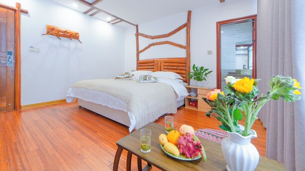 Ein Schlafzimmer mit einem hölzernen Bett, einem Nachttisch mit Blumen in einer Vase und einem Obstteller.