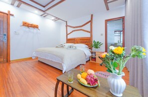 A bedroom with a wooden bed, a bedside table with a vase of flowers, and a fruit plate. - Easy House (Zhangjiajie)