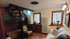 A cozy living room with a sofa, a chair, a staircase, and a radiator. - Maison du Soleil - a stone's throw from the sky, for those who love skiing and more (Maen)