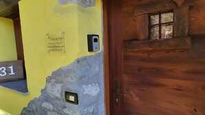 A rustic wooden door with a small window above it, a stone wall with a plaque, and a yellow wall with a number '31' sign. - Maison du Soleil - a stone's throw from the sky, for those who love skiing and more (Maen)