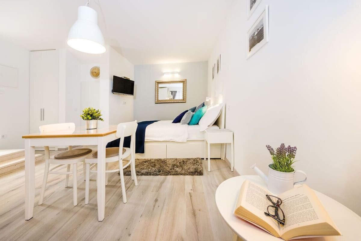 Ein modernes, helles Schlafzimmer mit Bett, Nachttischen, einem Schreibtisch und einem Sessel.