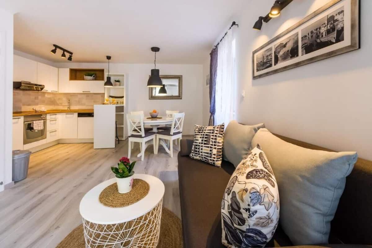 Ein modernes Wohnzimmer mit einer Couch, einem Esstisch und einer Küchenzeile.