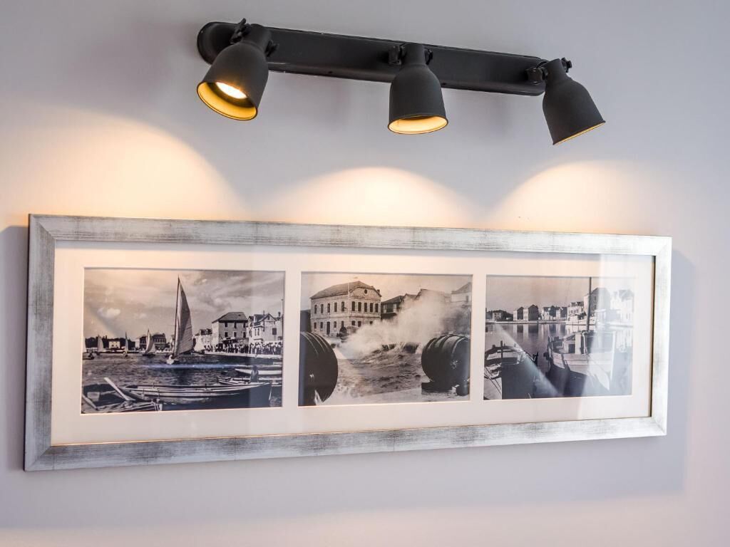 A framed photograph with three black and white images of historical scenes, mounted on a wall with a black ceiling light fixture above.