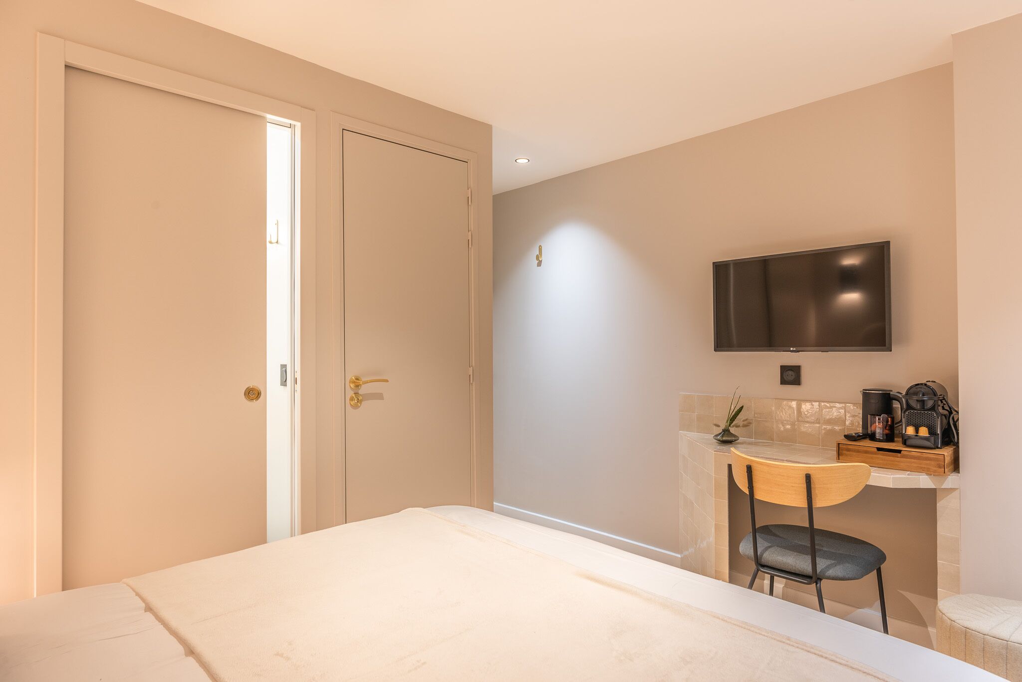 A bedroom with a bed, a desk, a chair, a television, and a door.