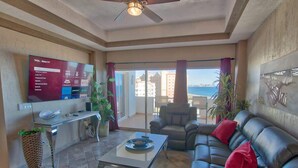 Ein Wohnzimmer mit Fernseher, Ledersofa und einem Balkon mit Blick.
