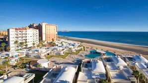 Ein Resort mit mehreren Gebäuden, einem Strand und einem Schwimmbad.