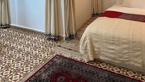 A room with a bed, a mirror, a painting, and patterned rugs. - Bab El Fen  (Tangier)