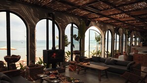 A spacious living area with a large TV, comfortable seating, and a view of the sea through arched windows. - @Before Sunset (Cesme)