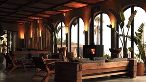 A spacious living area with a wooden sofa, chairs, and a fireplace. - @Before Sunset (Cesme)