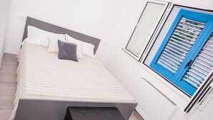 Ein Schlafzimmer mit einem Bett, einem Nachttisch und einem Fenster mit blauen Fensterläden.