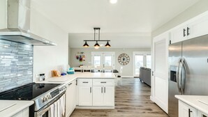 A modern kitchen with white cabinetry, a stainless steel refrigerator, and a black stove. - On Water's Edge - Literally, Direct Gulf Waterfront! (Freeport)