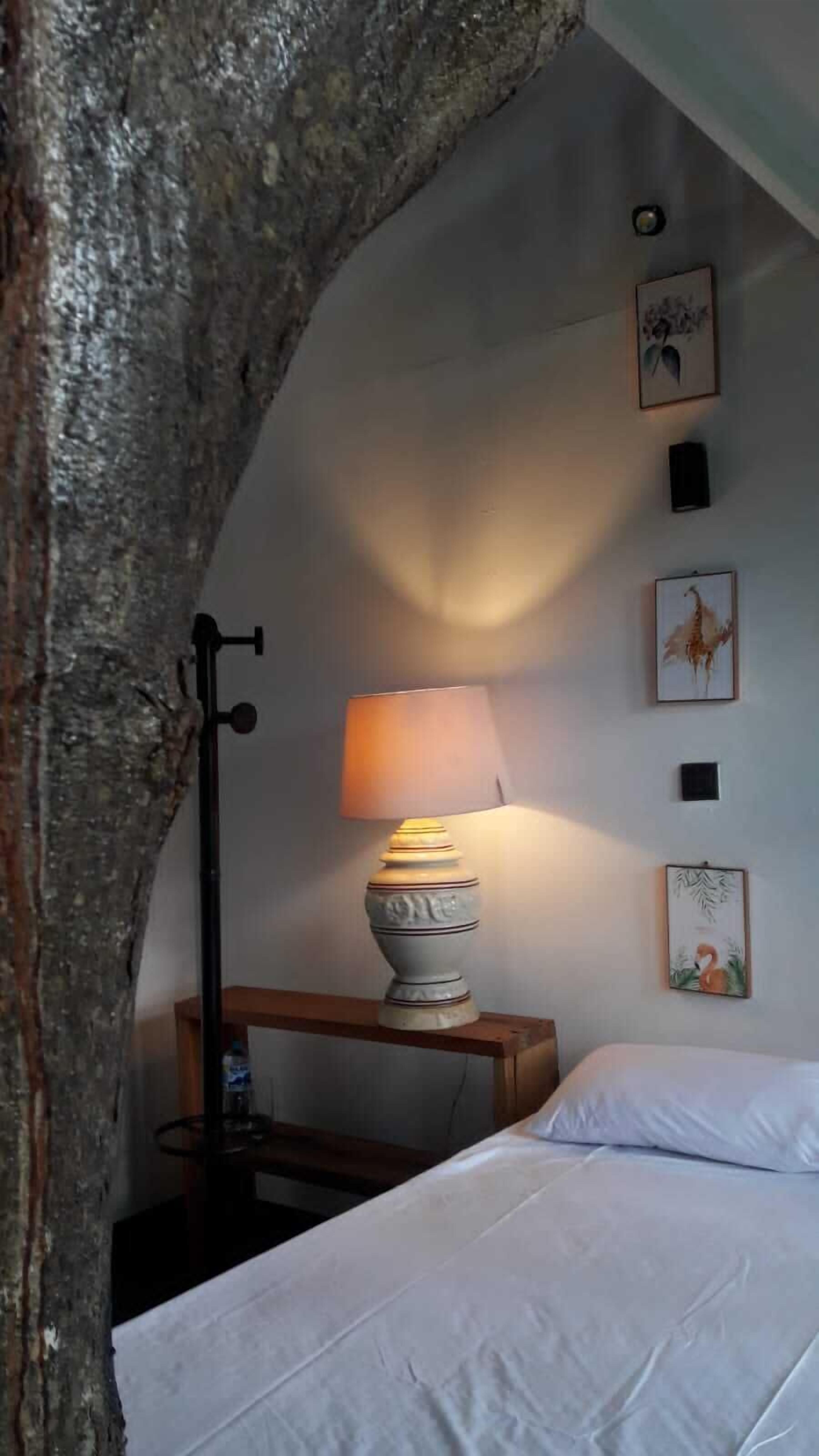 A bedroom with a bed, a lamp, and wall art.