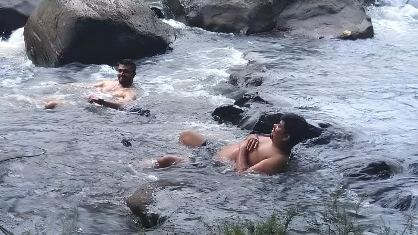 A river with rocks and people swimming.
