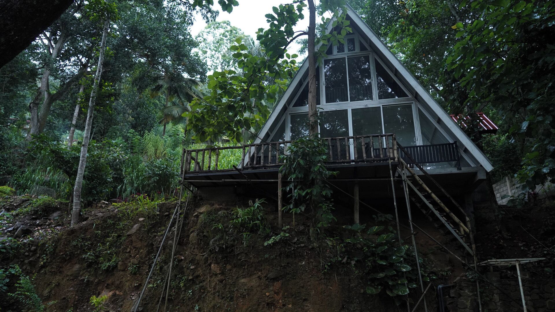 A wooden cabin with a balcony, surrounded by dense forest.