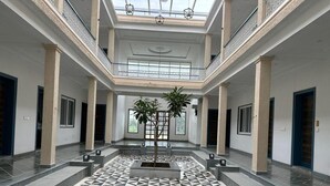A spacious atrium with a geometric patterned floor, a central plant, and a high ceiling with skylights. - The Arham Resort (Udaipur)