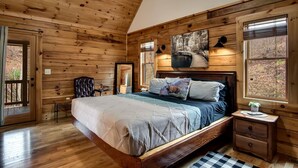 Ein Schlafzimmer einer Holzhütte mit Bett, Nachttisch, Lampe und einem Bild an der Wand.