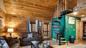 Ein Holzinnenraum mit Treppe, einer Couch, einem Couchtisch und einer Lampe.