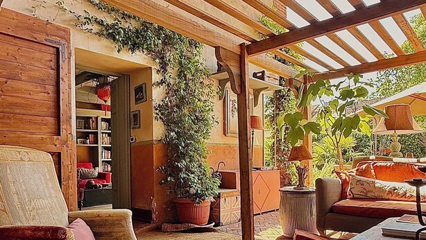 A cozy, open-plan living area with a wooden ceiling, a comfortable sofa, a coffee table, and a large potted plant. - 18th century residence with garden and sauna, close to the Navigli District (Milano)