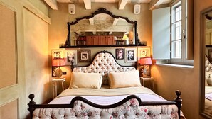 A classic four-poster bed with a floral headboard, flanked by two bedside tables with lamps, in a room with a high ceiling and exposed beams. - 18th century residence with garden and sauna, close to the Navigli District (Milano)