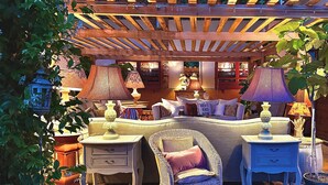A cozy outdoor seating area with a wooden pergola, wicker furniture, and various lamps. - 18th century residence with garden and sauna, close to the Navigli District (Milano)