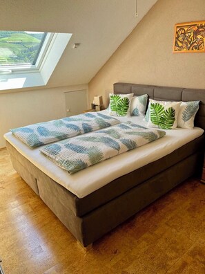 Relax in this serene bedroom with a large bed, leaf-patterned pillows, and a skylight above.