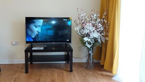 A television on a stand in a room with wooden flooring and a vase of flowers. - House, Sleeps 3 With Balcony and Parking (Smethwick)