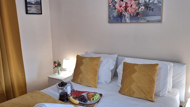 A hotel room with a neatly made bed, a painting on the wall, and a breakfast tray on the bed. - House, Sleeps 3 With Balcony and Parking (Smethwick)