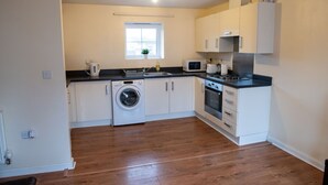 A compact kitchen with a washing machine, microwave, and oven. - House, Sleeps 3 With Balcony and Parking (Smethwick)