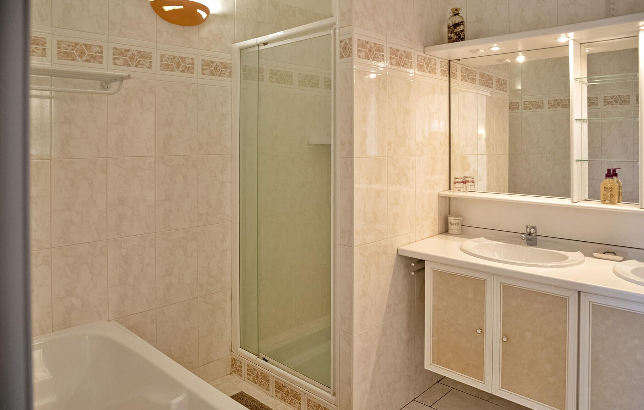 A modern bathroom with a glass-enclosed shower, a white sink, and a large mirror.