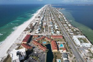 An aerial view of a coastal resort with a long beachfront, a marina, and a central road. - Incredible Huge Townhome with Pool and Steps to Gulf! You will love this Place! (Pensacola Beach)