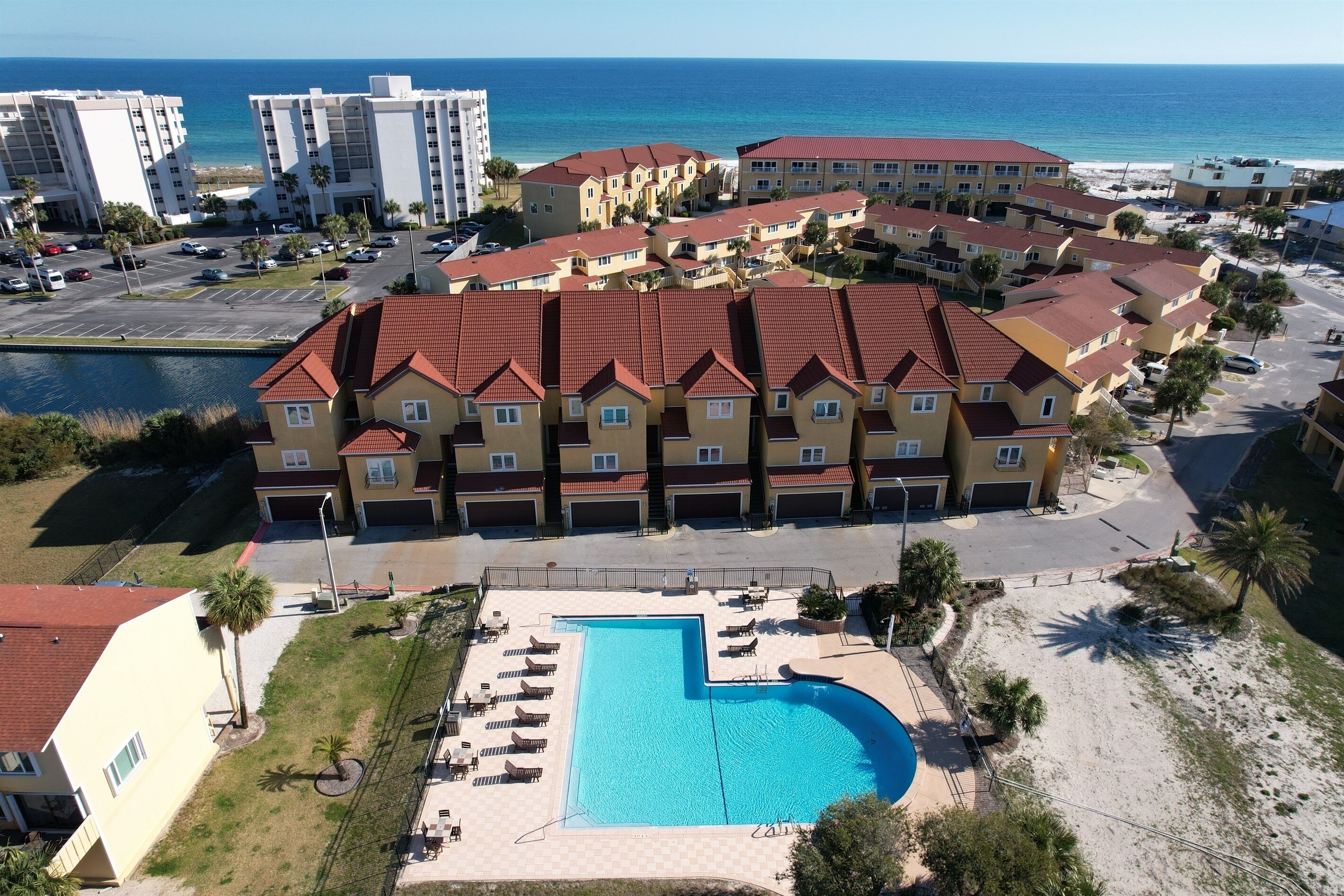 A hotel with a swimming pool, multiple buildings, and a view of the ocean.