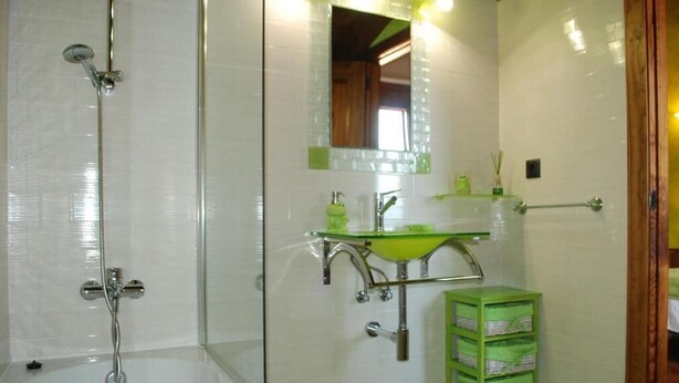 A bathroom with a glass-enclosed shower, a green sink, and a mirror above it. - posada la fabula (Santillana del Mar)