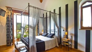 A bedroom with a four-poster bed, a small bedside table with a lamp, and a chair. - posada la fabula (Santillana del Mar)