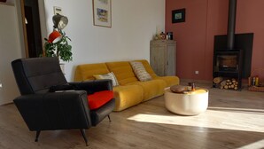 A living room with a yellow sofa, a black armchair, a round coffee table, and a fireplace.