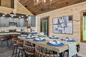 Una cocina moderna con armarios grises, una isla central y una zona de comedor para seis personas con sillas de cuero.