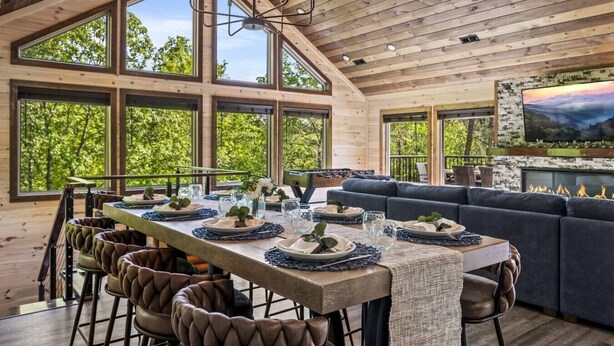A wooden interior with a dining area, sofa, and fireplace.