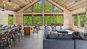 A log cabin interior with a dining area, sofa, and large windows.