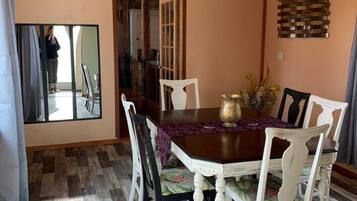 A dining area with a wooden ceiling, a table with chairs, and a mirror on the wall.
