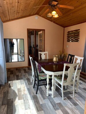 Uma sala de jantar com teto de madeira, uma mesa com cadeiras e um espelho na parede.